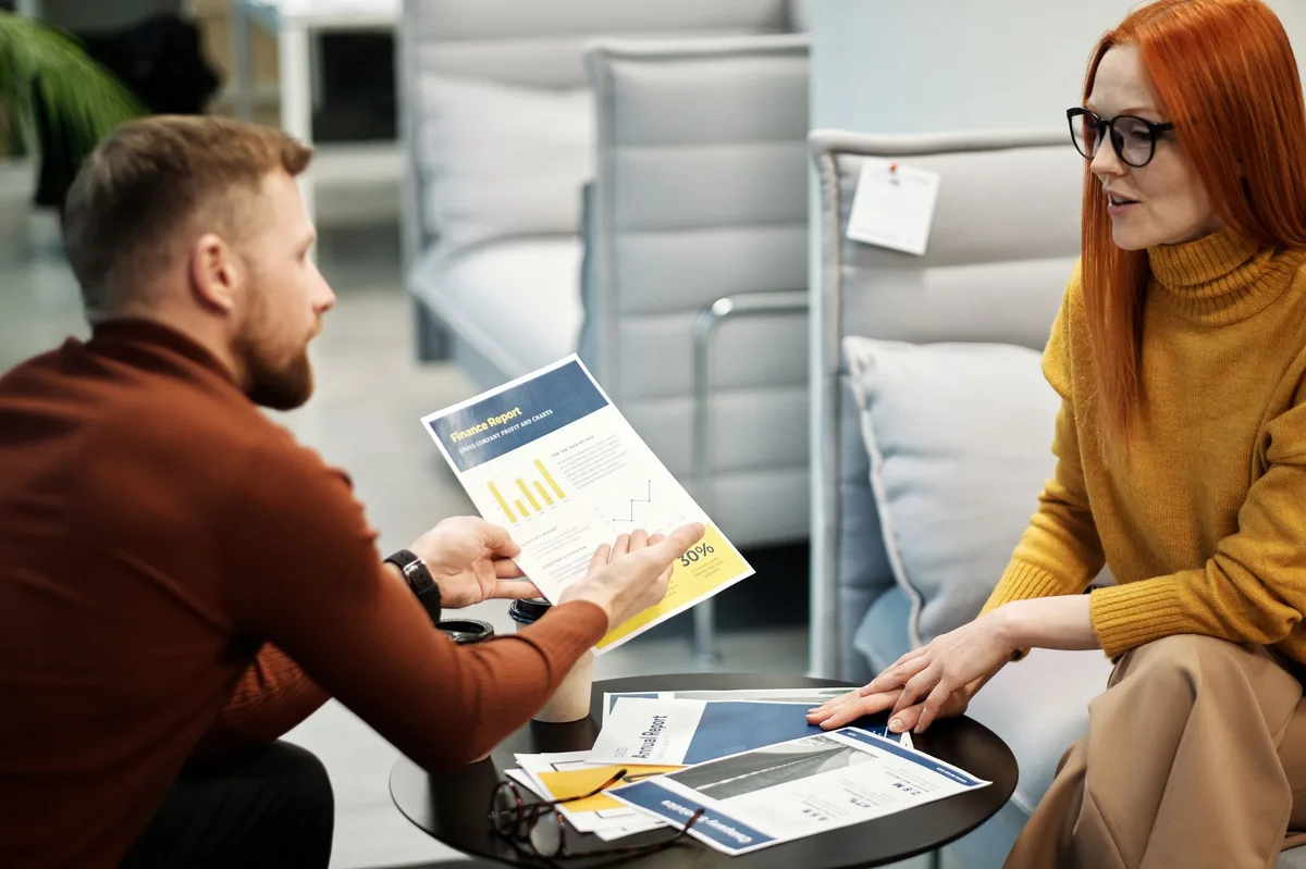 Two people in professional discussion reviewing financial documents together