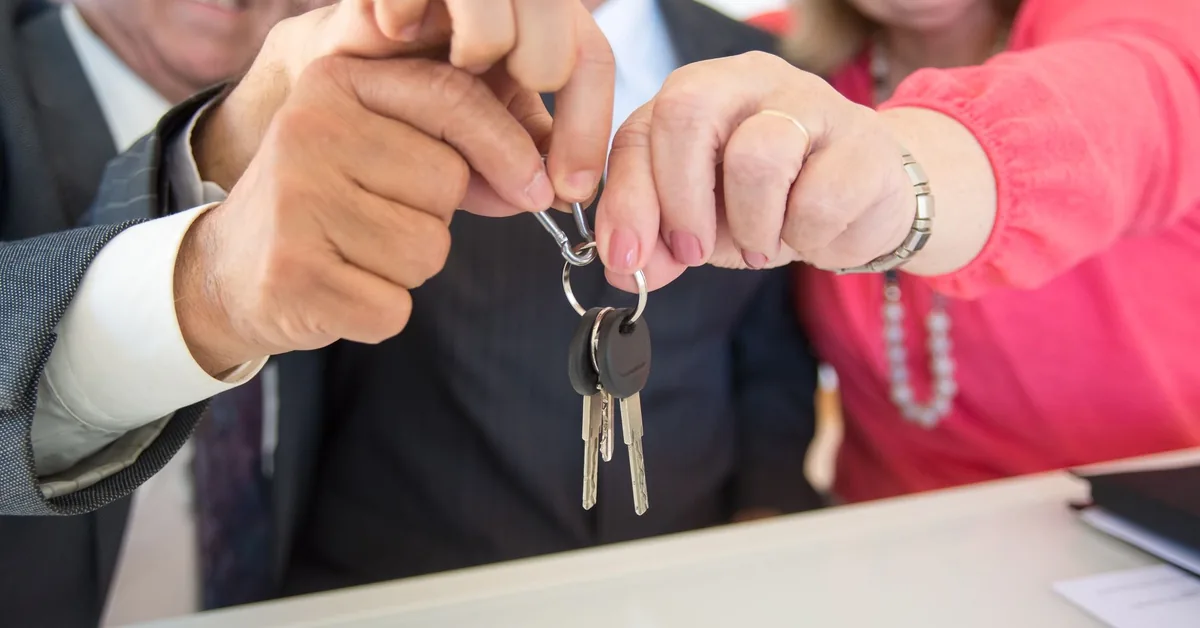 Two professionals shaking hands across a desk during a mortgage refinancing consultation
