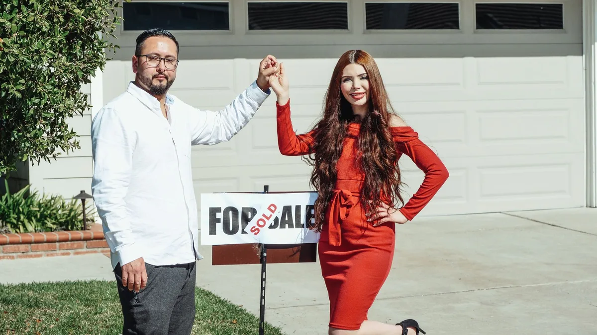 First home buyers holding house keys in front of their new property