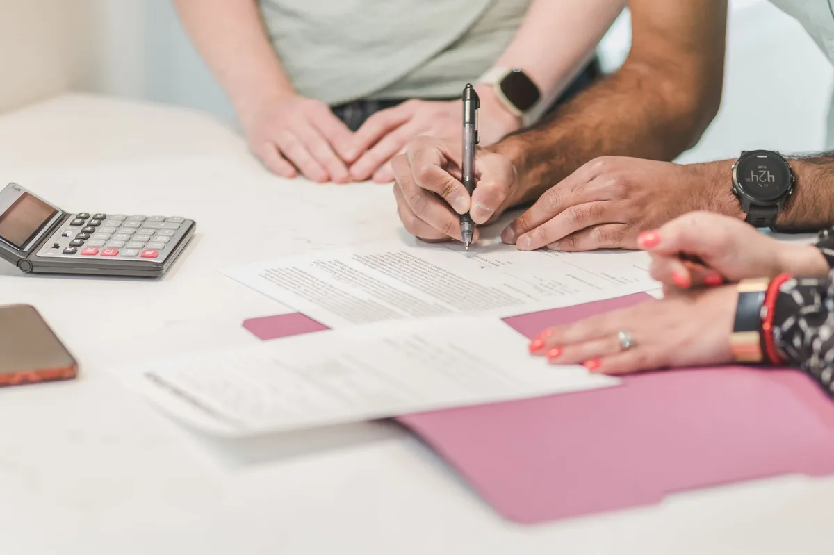 Refinance documents and calculator on desk with mortgage paperwork