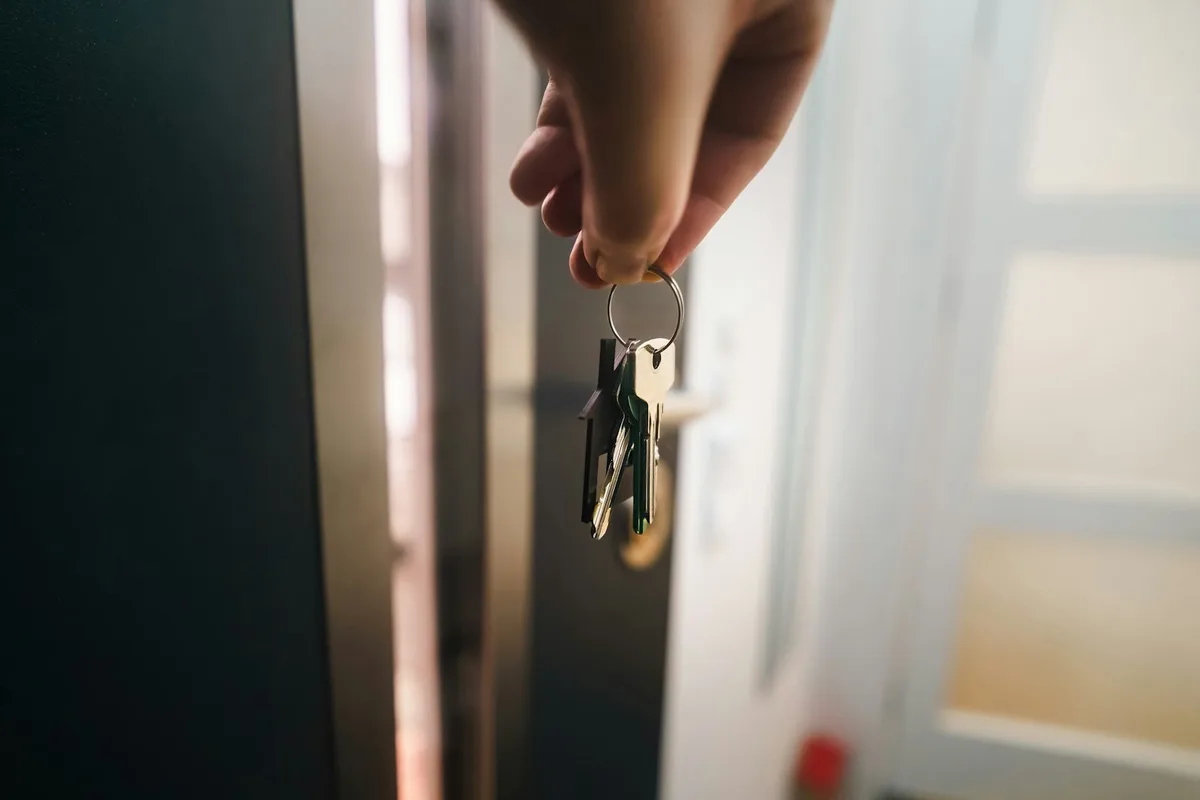 Young couple holding house keys in front of their new home