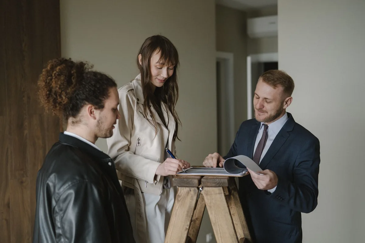 Person signing a real estate contract with pen and documents on desk