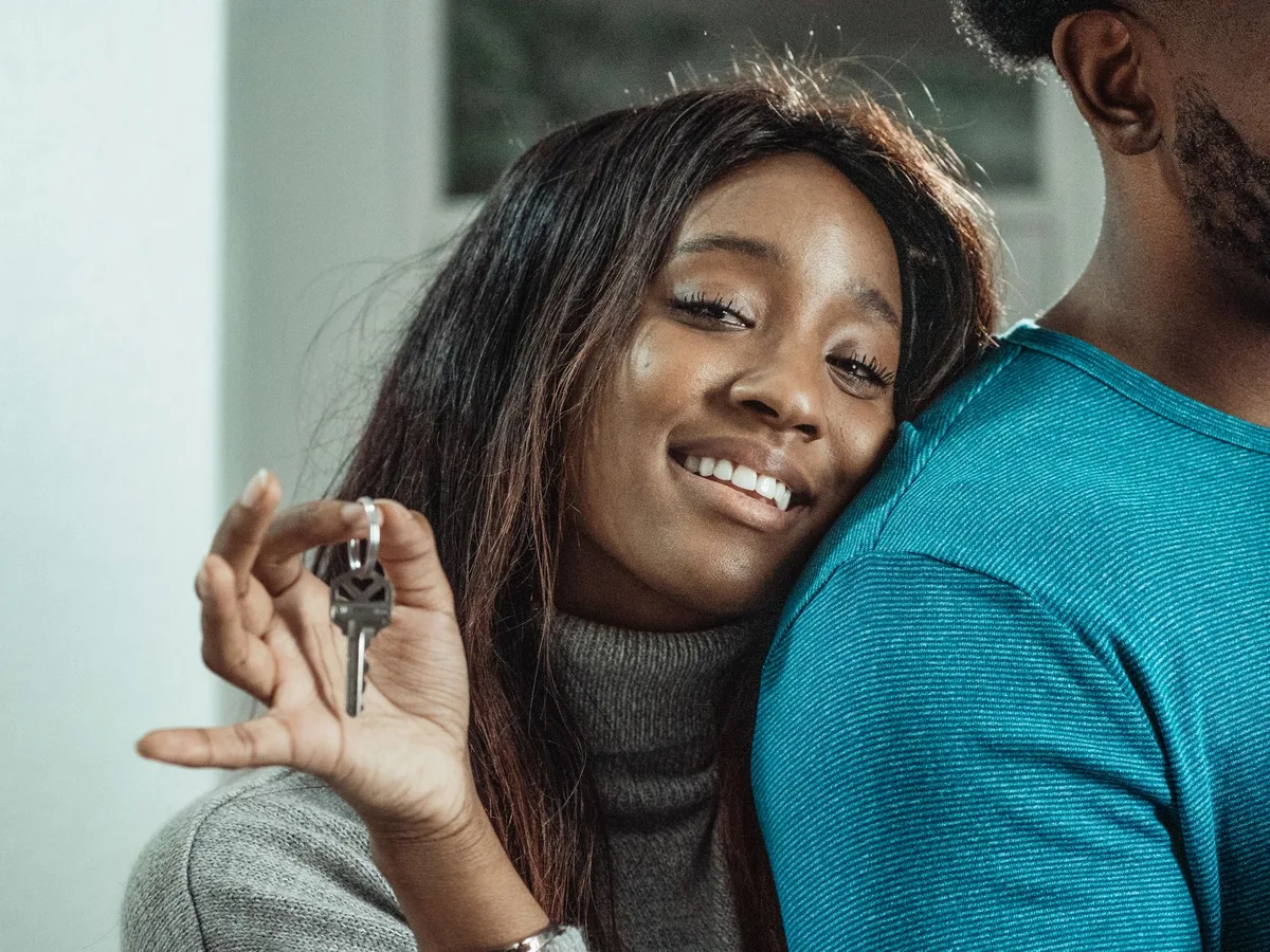 Young couple celebrating in front of their first home with keys