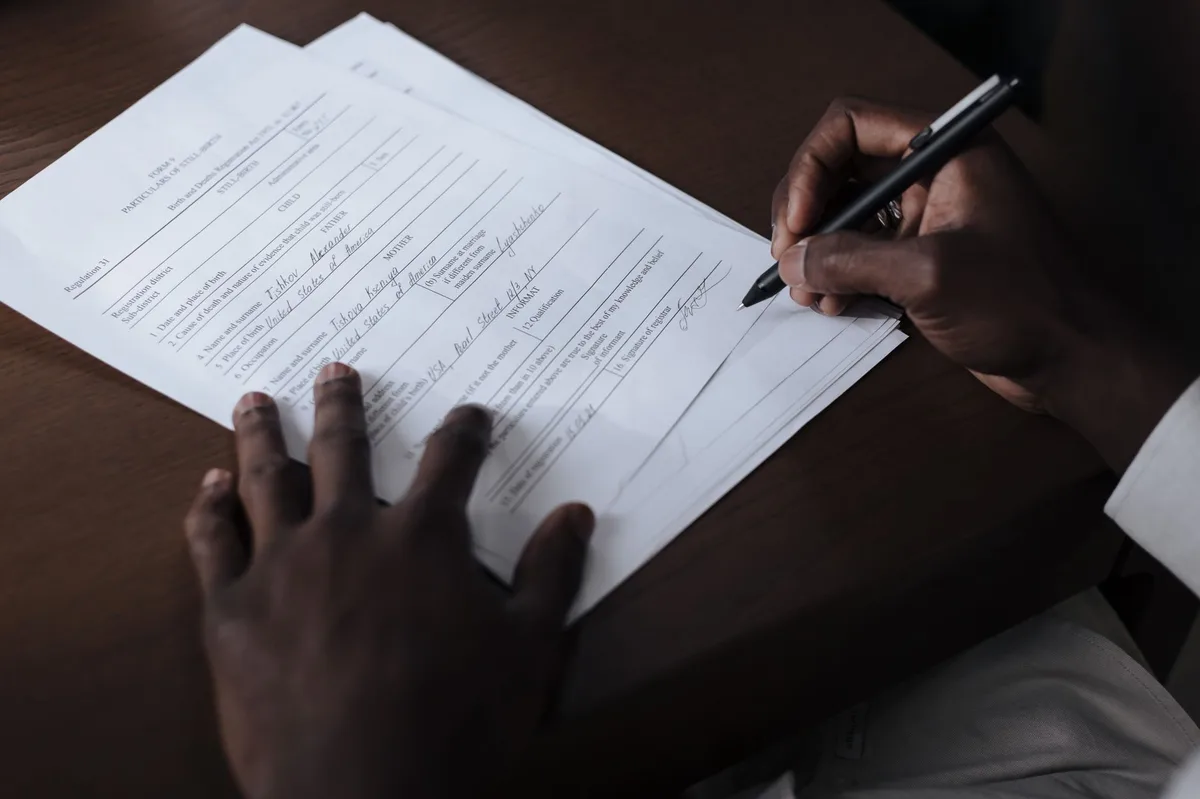 Person signing mortgage contract documents with pen