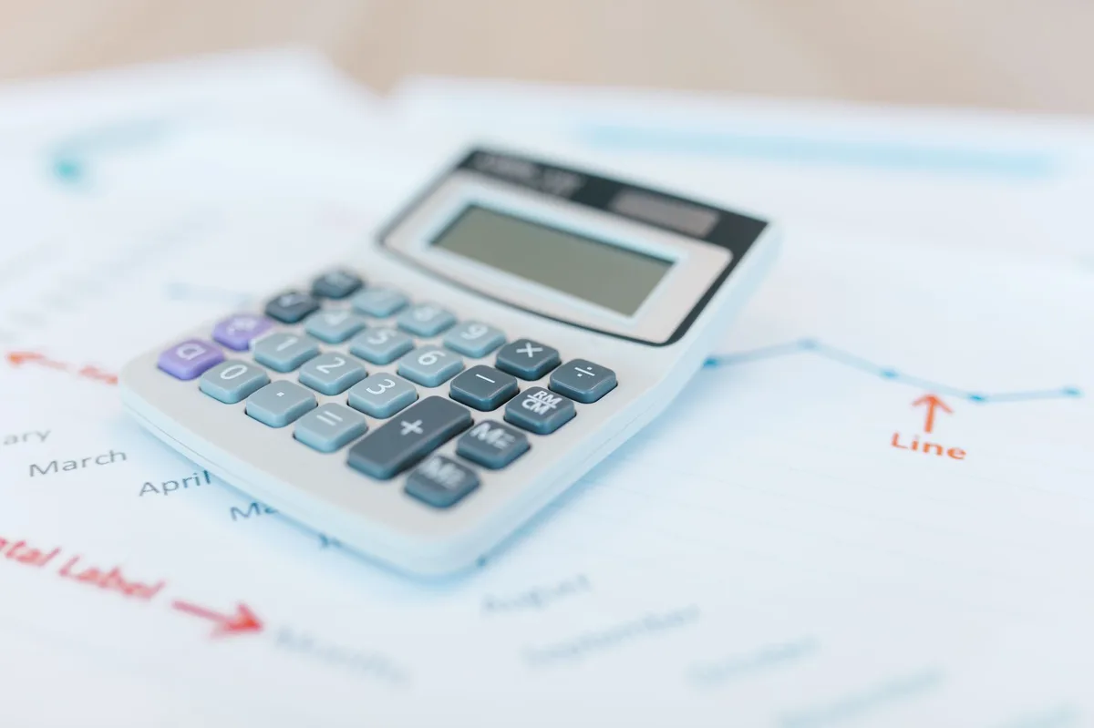 Calculator resting on mortgage payment documents with spreadsheet