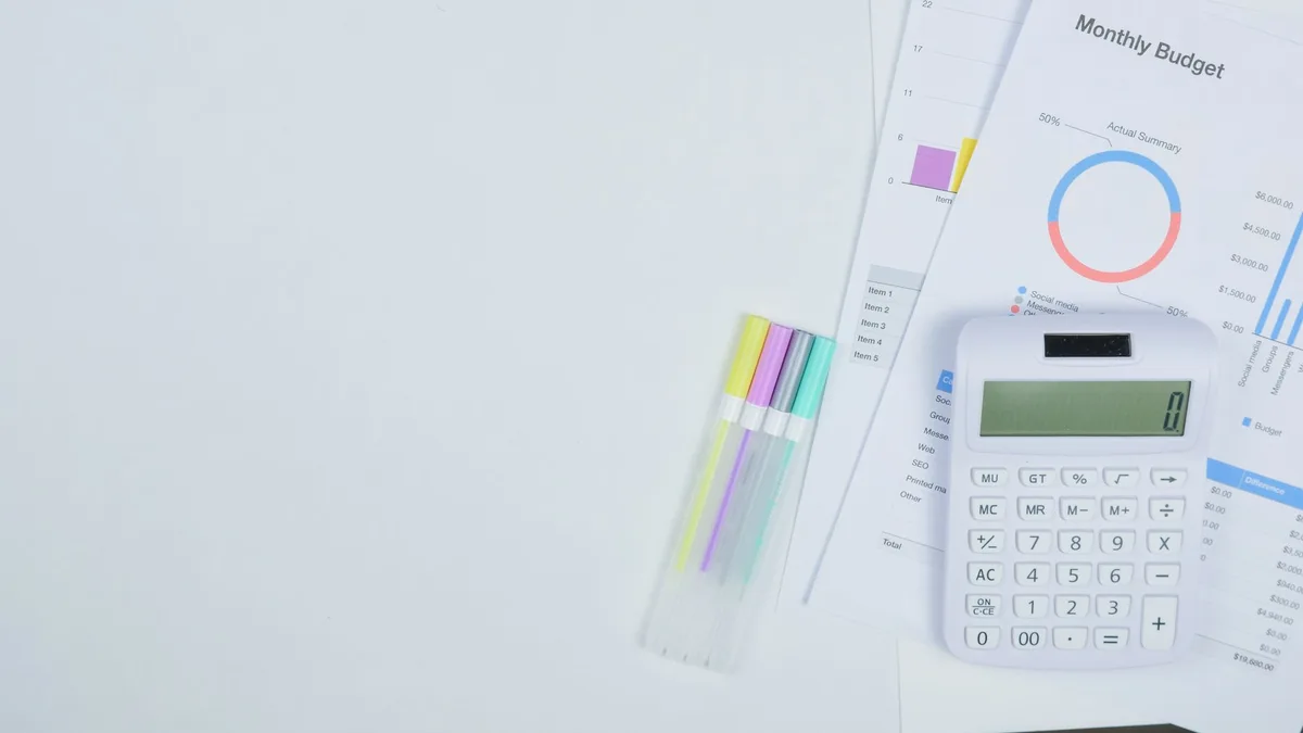 Calculator resting on financial documents showing budget calculations
