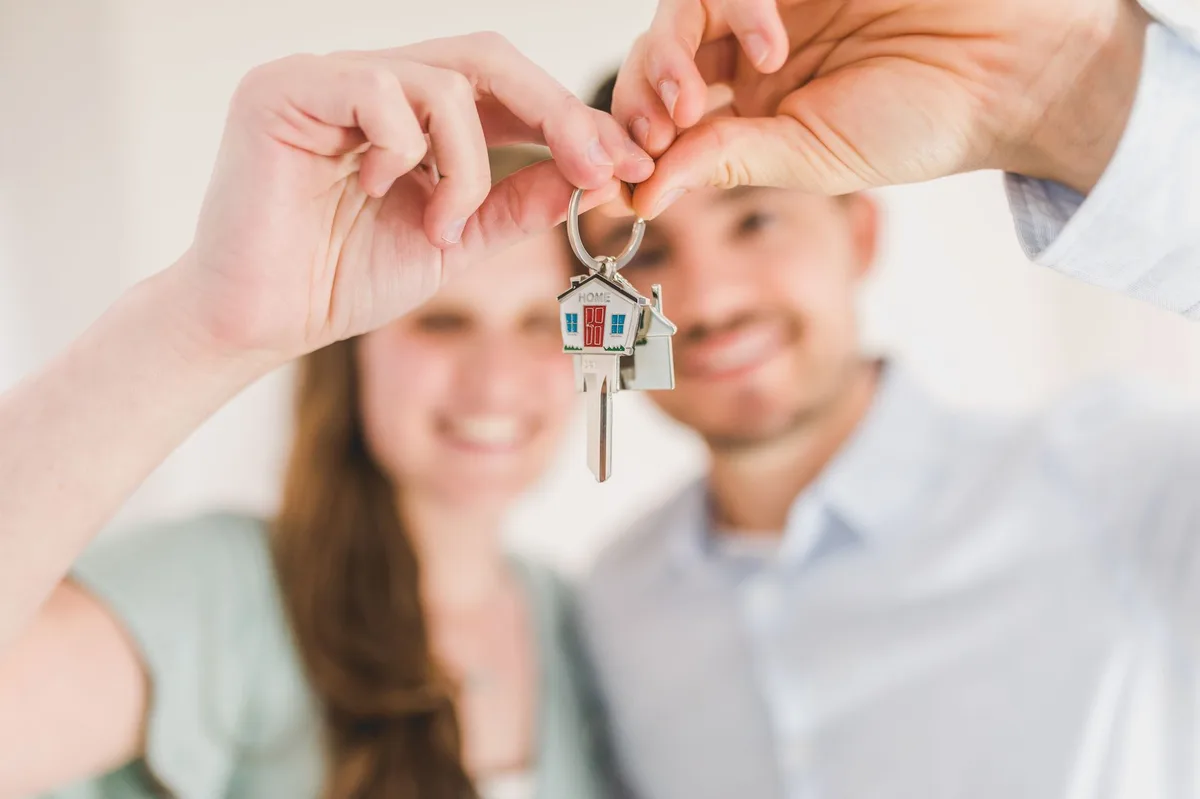 A couple holding keys in front of their first home