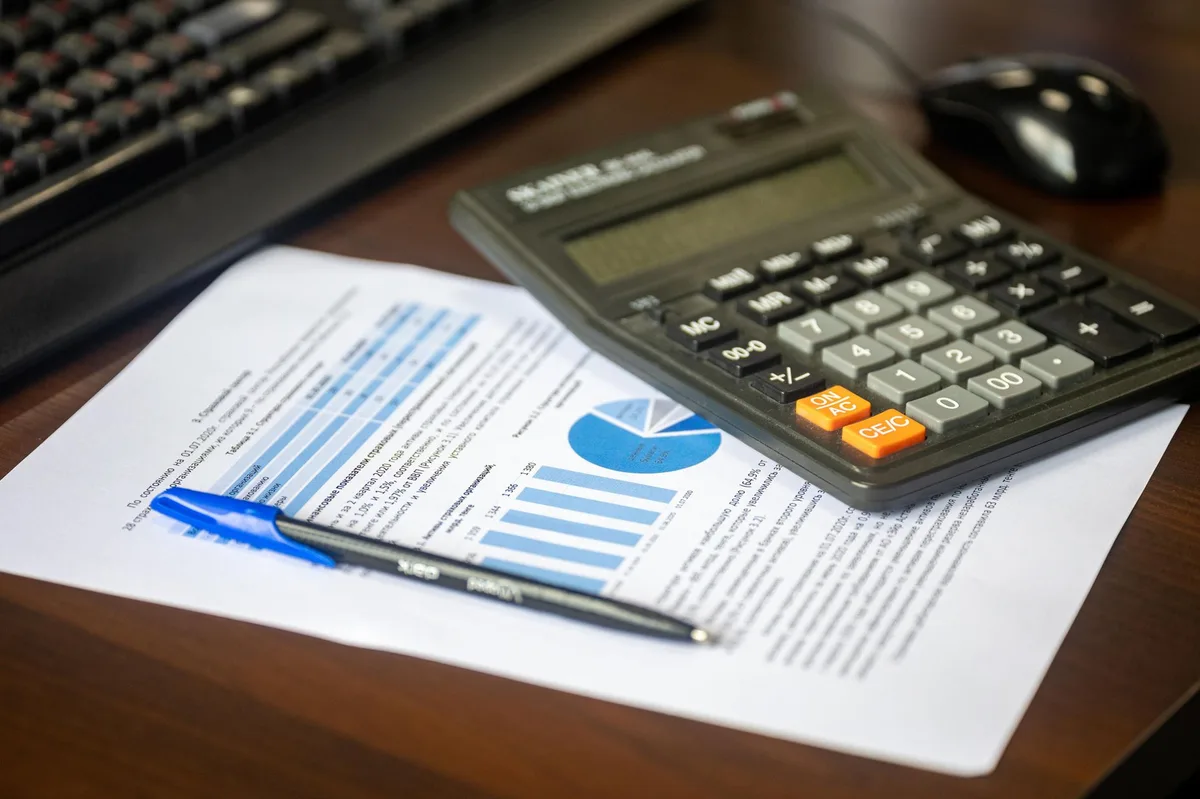 Calculator resting on mortgage application documents with a pen