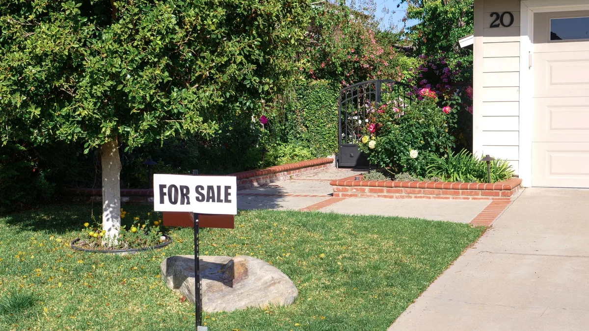 A residential property with a for-sale sign in the garden