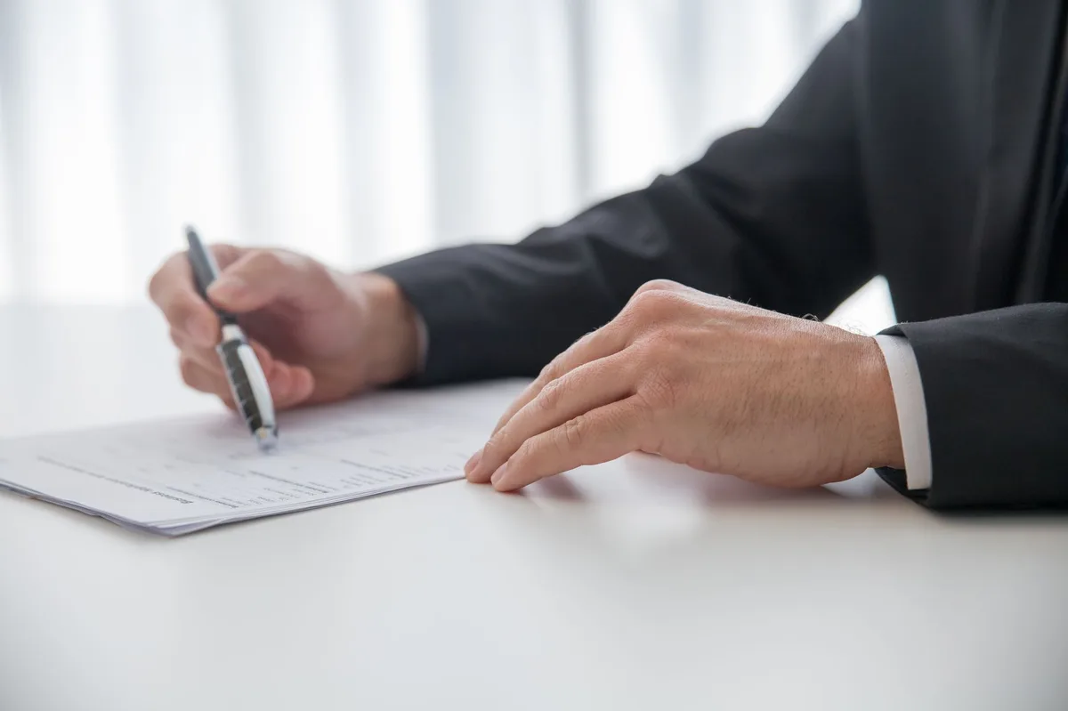 Person signing mortgage contract documents with pen on desk