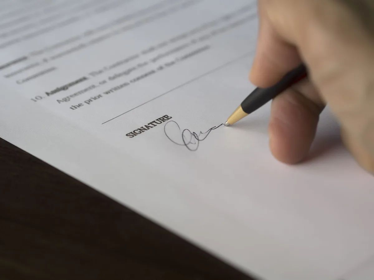 Person signing mortgage contract documents with pen
