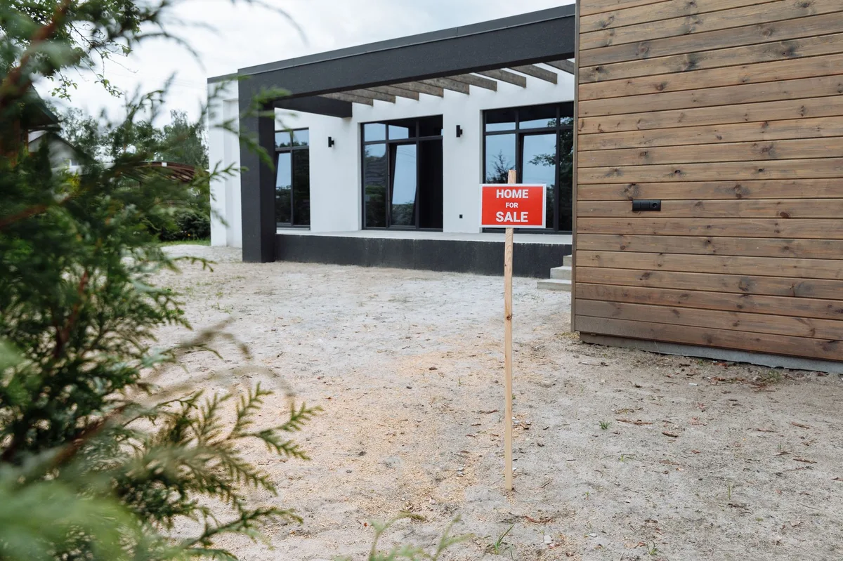 House with for sale sign in front yard