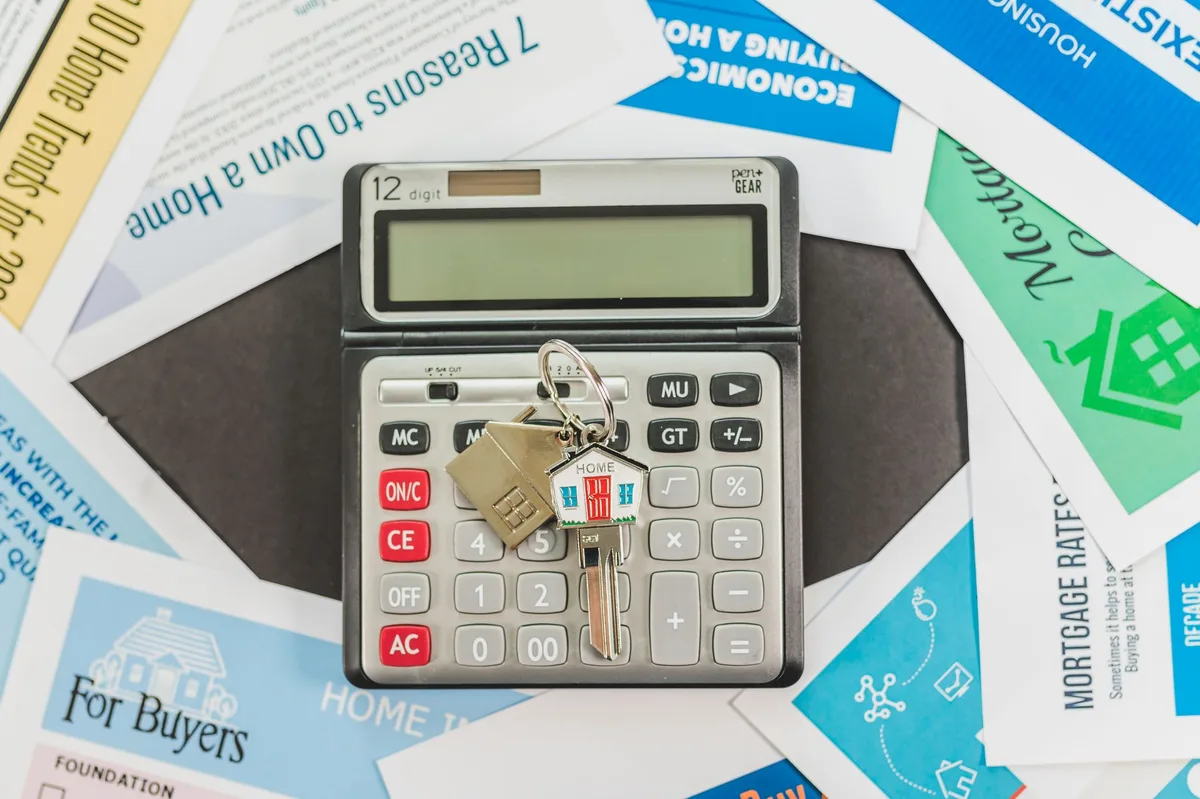 Calculator resting on mortgage documents with pen and paperwork showing loan comparison