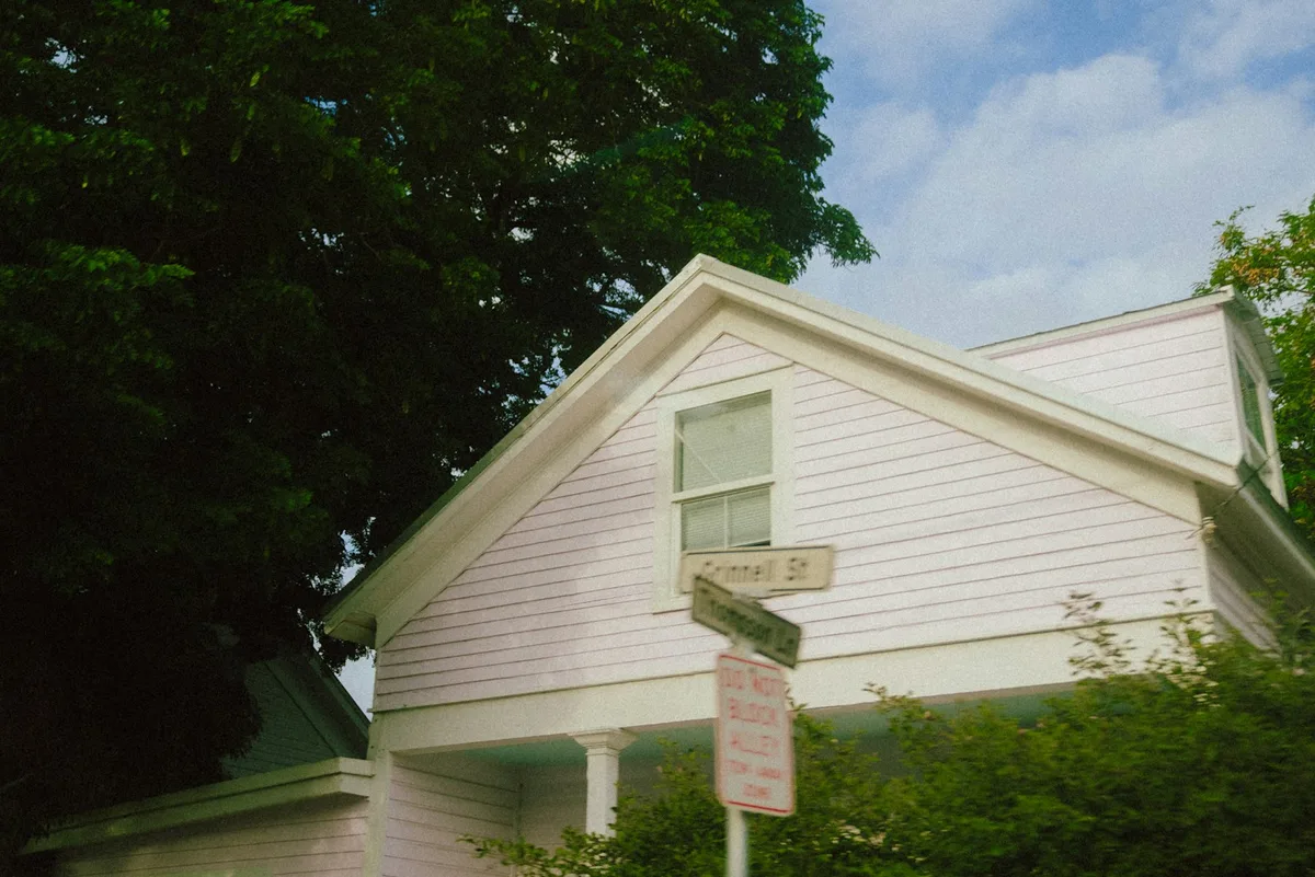 A for-sale sign in front of a suburban home during summer